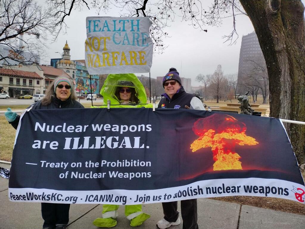 Anti-nuclear weapons protestors hold signs at rally.